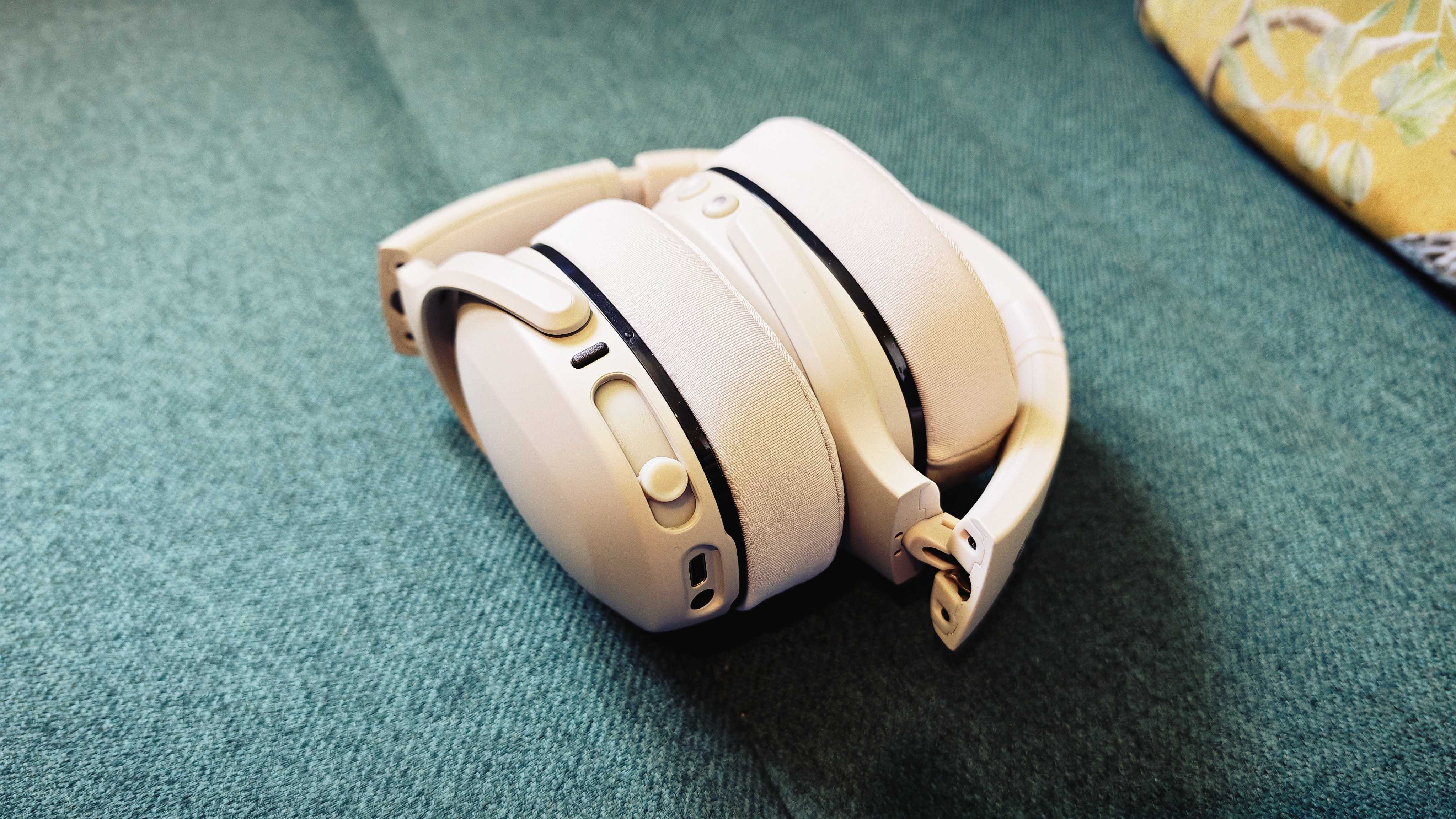 A white pair of Skullcandy Crusher 540 Active headphones on a green sofa