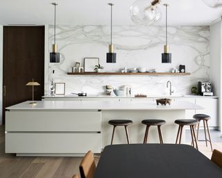 Modern white kitchen ideas with an island with handleless drawers and a large white and grey marble backsplash