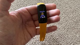 A hand holding a Fitbit Inspire 3 showing a sleep score