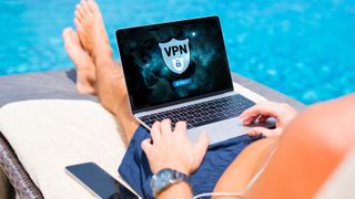 Man by the side of a pool using a VPN on a laptop