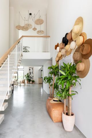 Decorative straw hats line a white hallway wall in contemporary entryway space