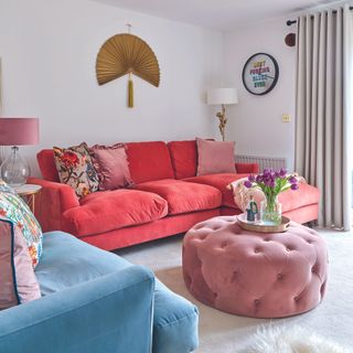 Living room with red sofa, pink ottoman and cushions.