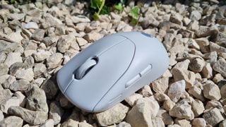 The Alienware Pro Wireless Gaming Mouse on white gravel, on a lovely summers day