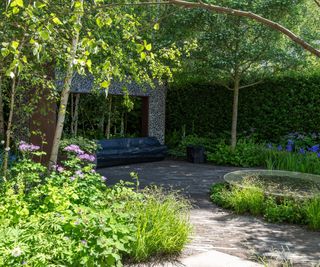 A peaceful and semi shaded garden area with outdoor sofa and water feature