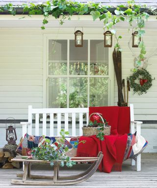 A porch area with white wood paneling, a white wooden bench and a child's snow sleigh