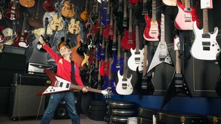 Kid in a guitar store playing a Gibson Flying V