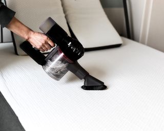 Person vacuuming bed