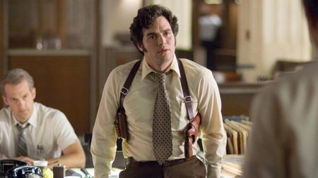 Mark Ruffalo dressed up as a detective leaning against a desk in Zodiac