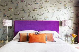 bedroom with wallpaper and purple velvet headboard