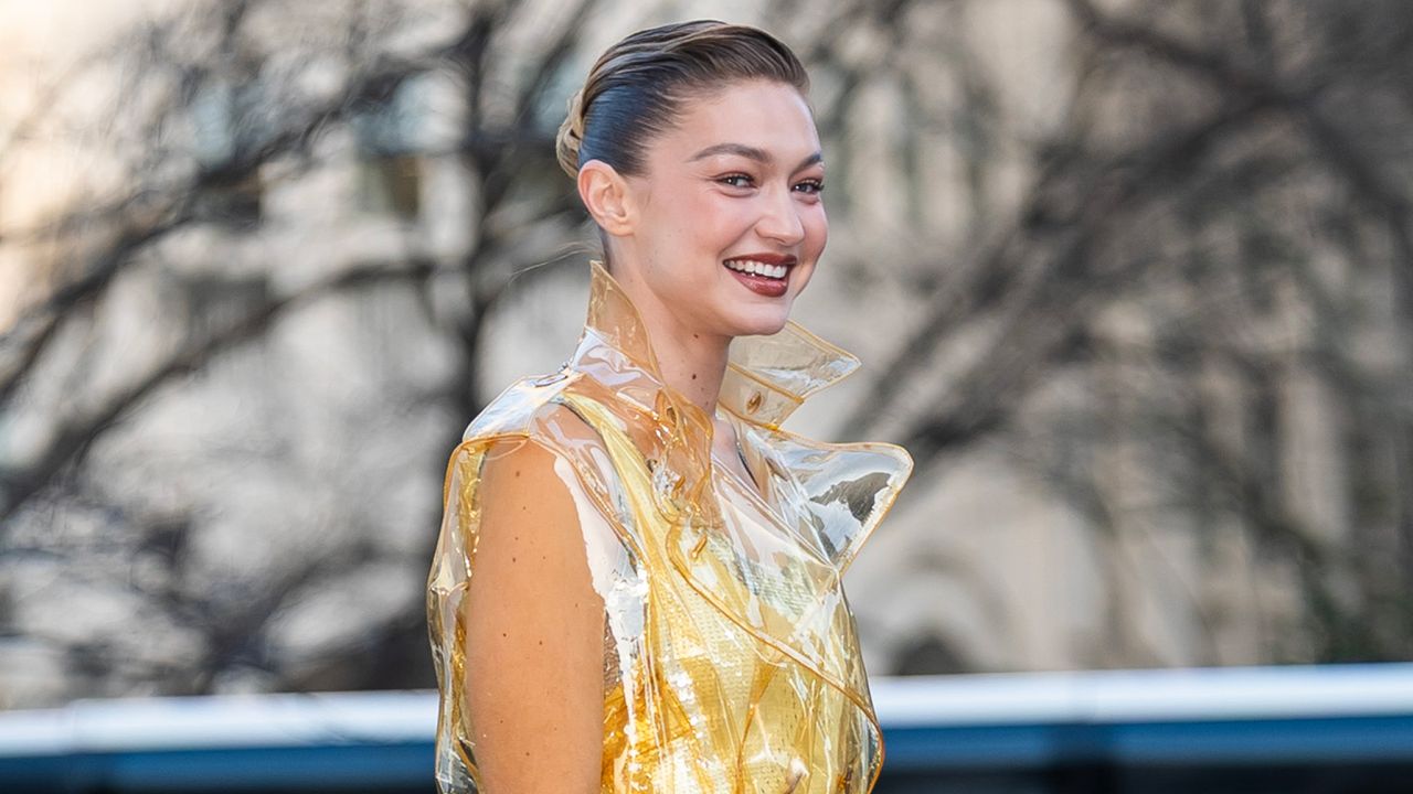 Gigi Hadid in new york city wearing a transparent trench coat with a butter yellow naked dress 