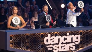 The Dancing With The Stars judges hold up all of their 8 paddles in response to a performance on the dance floor. They seem impressed.