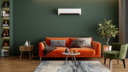orange sofa in dark green living room with air conditioning unit