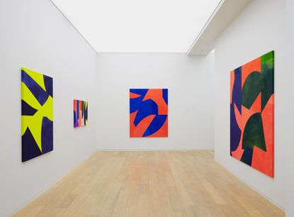 Abstract bright coloured paintings in white walled gallery