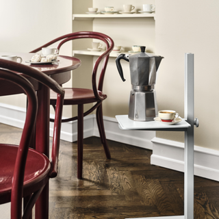 Silver cafetiere with coffee cup next to dining chairs