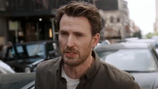 Chris Evans talking with cars behind him in Materialists. 