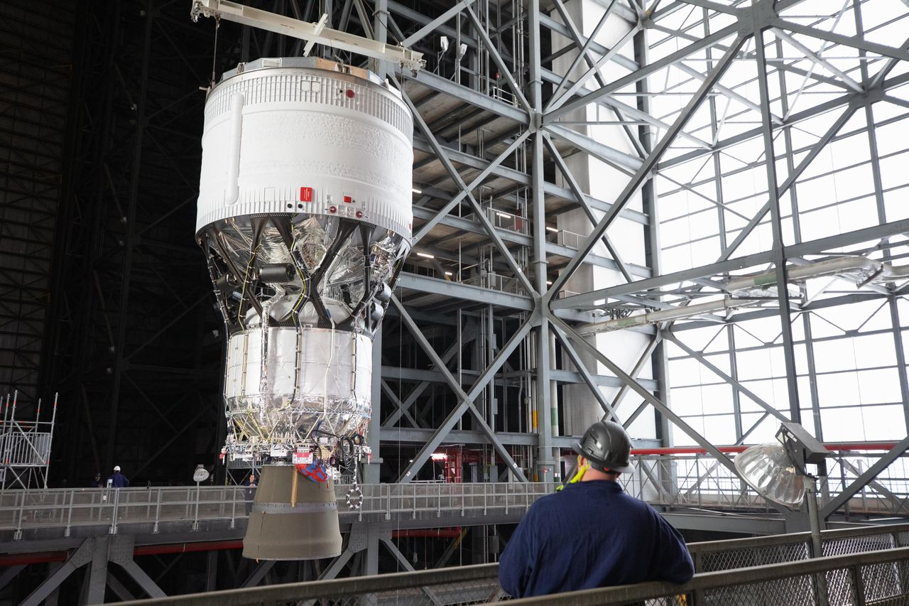 a large section of a rocket is hoisted in a factory