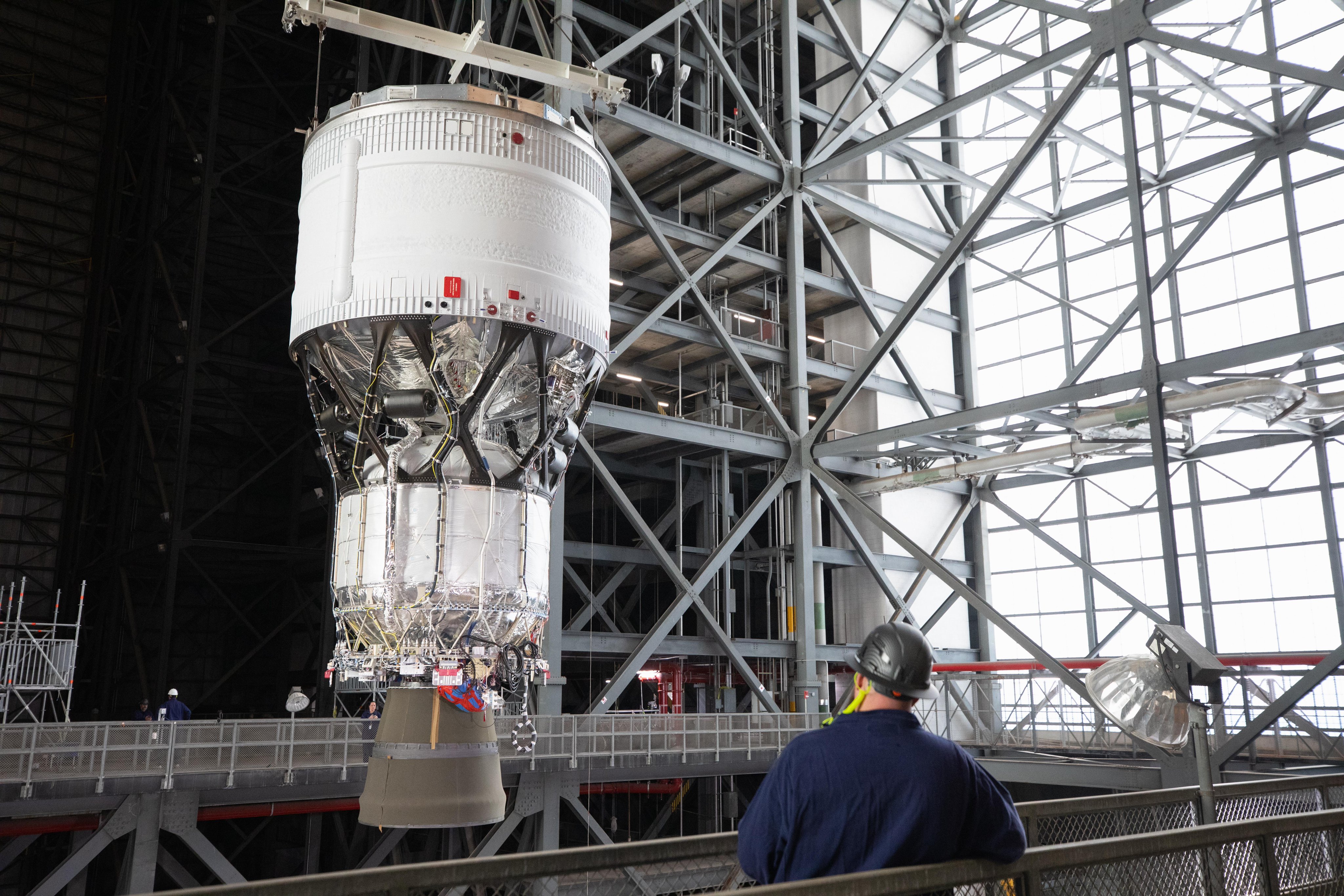 a large section of a rocket is hoisted in a factory