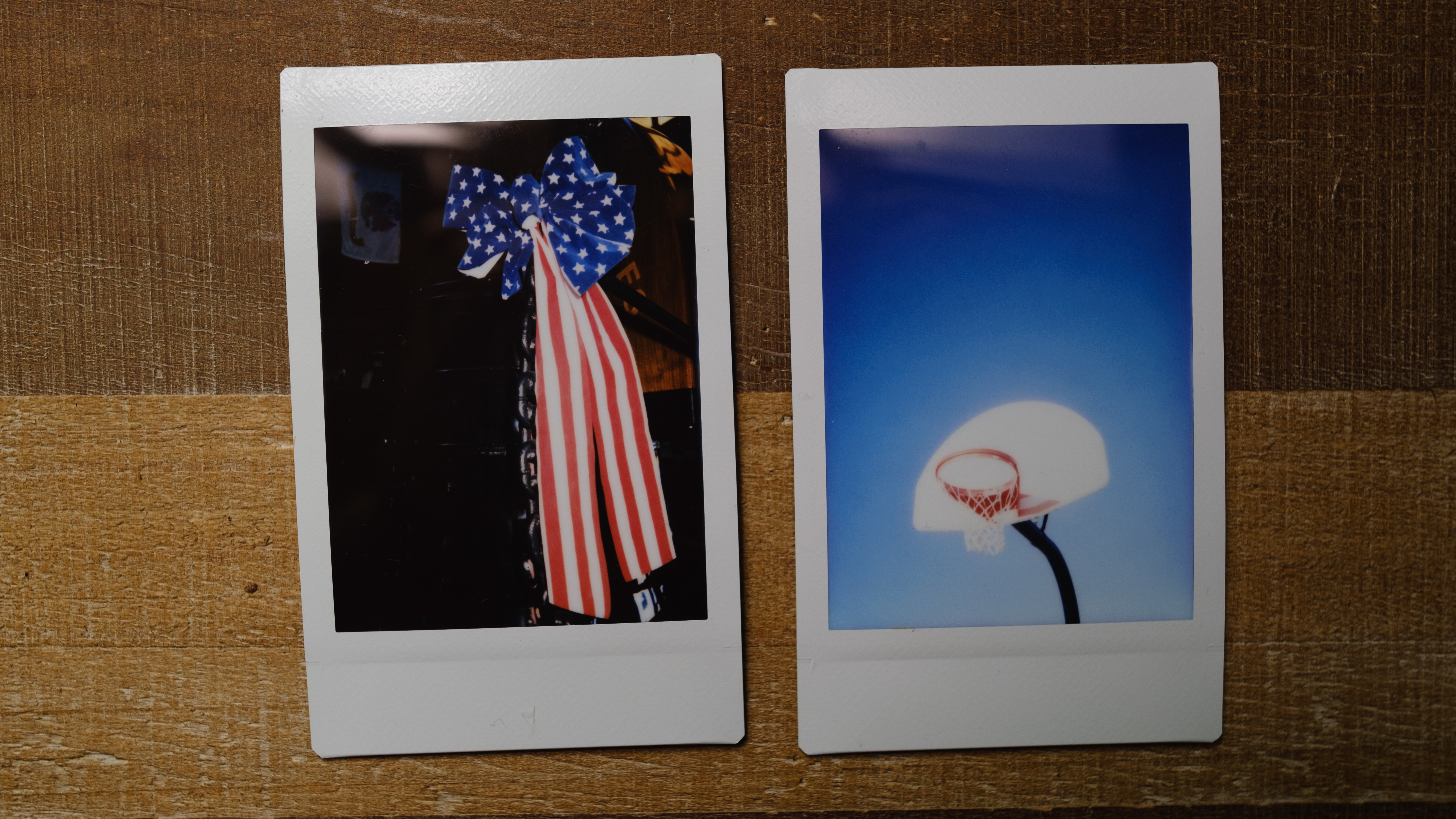 Two images from the Instax Mini SE sit on a table, one of a patriotic decoration and one of a basketball hoop