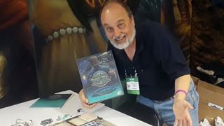 Alan Emrich holding a Nemo's War tabletop game box at a 2018 gaming convention