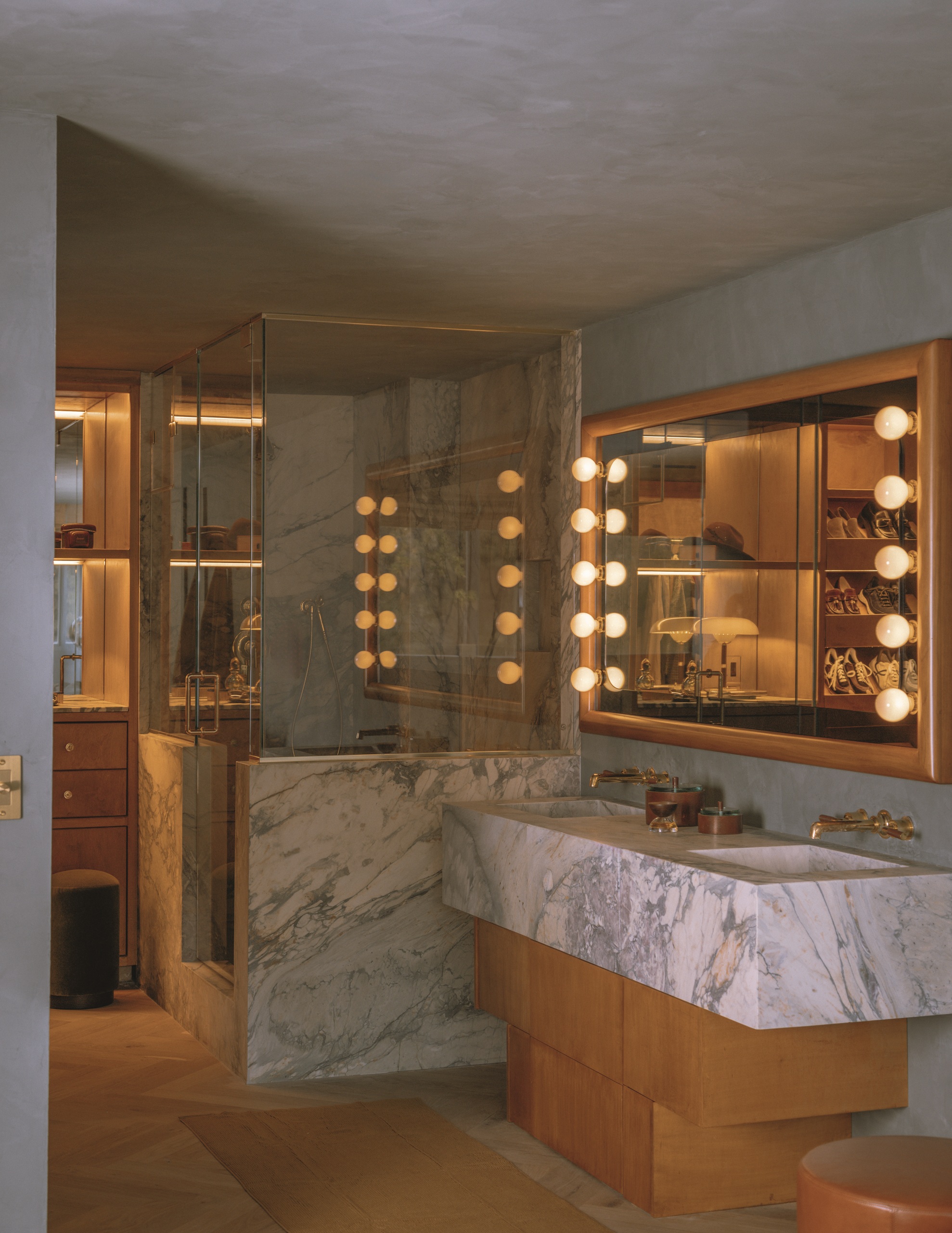 modern bathroom with plastered ceiling, marble and timber vanity, window with vanity-style bulbs, and an enclosed marble and glass shower