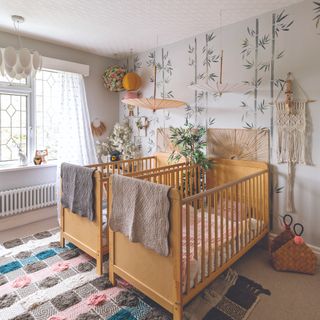 Two twin wooden cots in front of leafy green pattenred wall