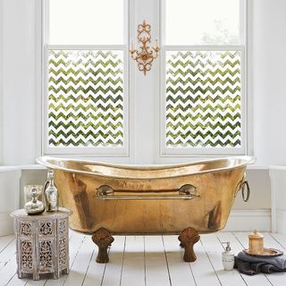 White bathroom with green patterned window film and copper bathtub