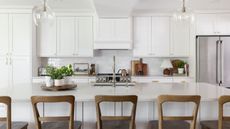 A white kitchen with art, cutting boards, and lamps decorating the countertops