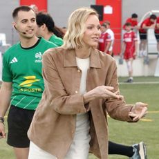 Princess Charlene wearing a brown jacket catching a ball