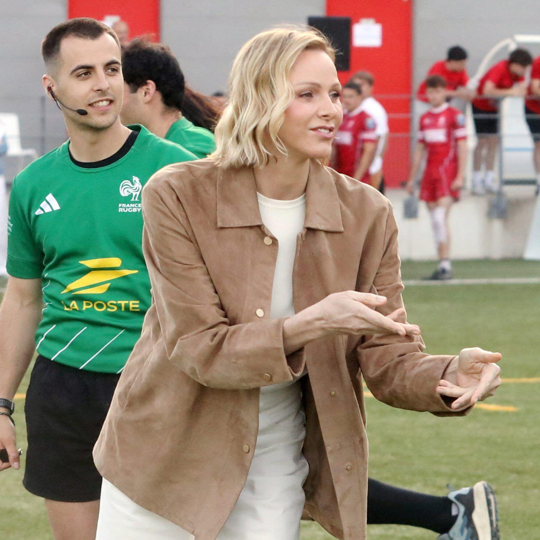 Princess Charlene wearing a brown jacket catching a ball