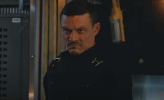 Luke Evans scowls while waiting in a cargo hold in The Fate of the Furious.