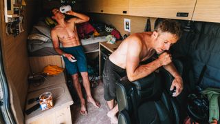 Alex Honnold and Tommy Caldwell eating and drinking on a break in their support van.