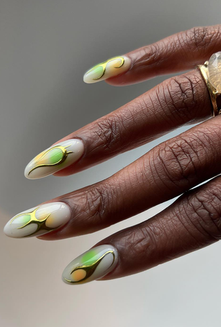 A manicure featuring gold and green flames by Paragon Nails.