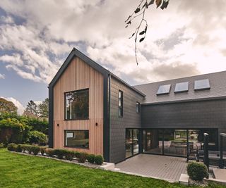 external shot of large house finished in black tiles with face end of large gable end clad in timber from floor to roof