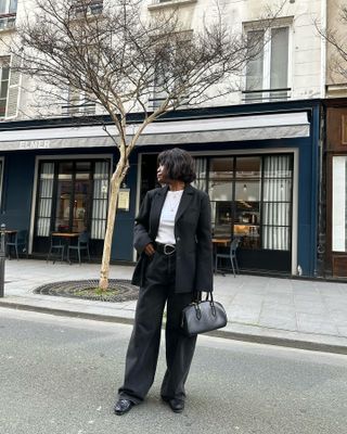 French woman wears baggy black jeans, a white t-shirt, black blazer and black woven loafers.