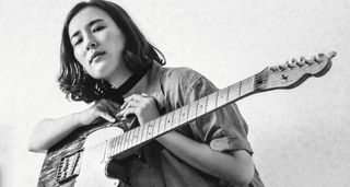 A black-and-white photo of Lea Thomas with her T-style electric guitar