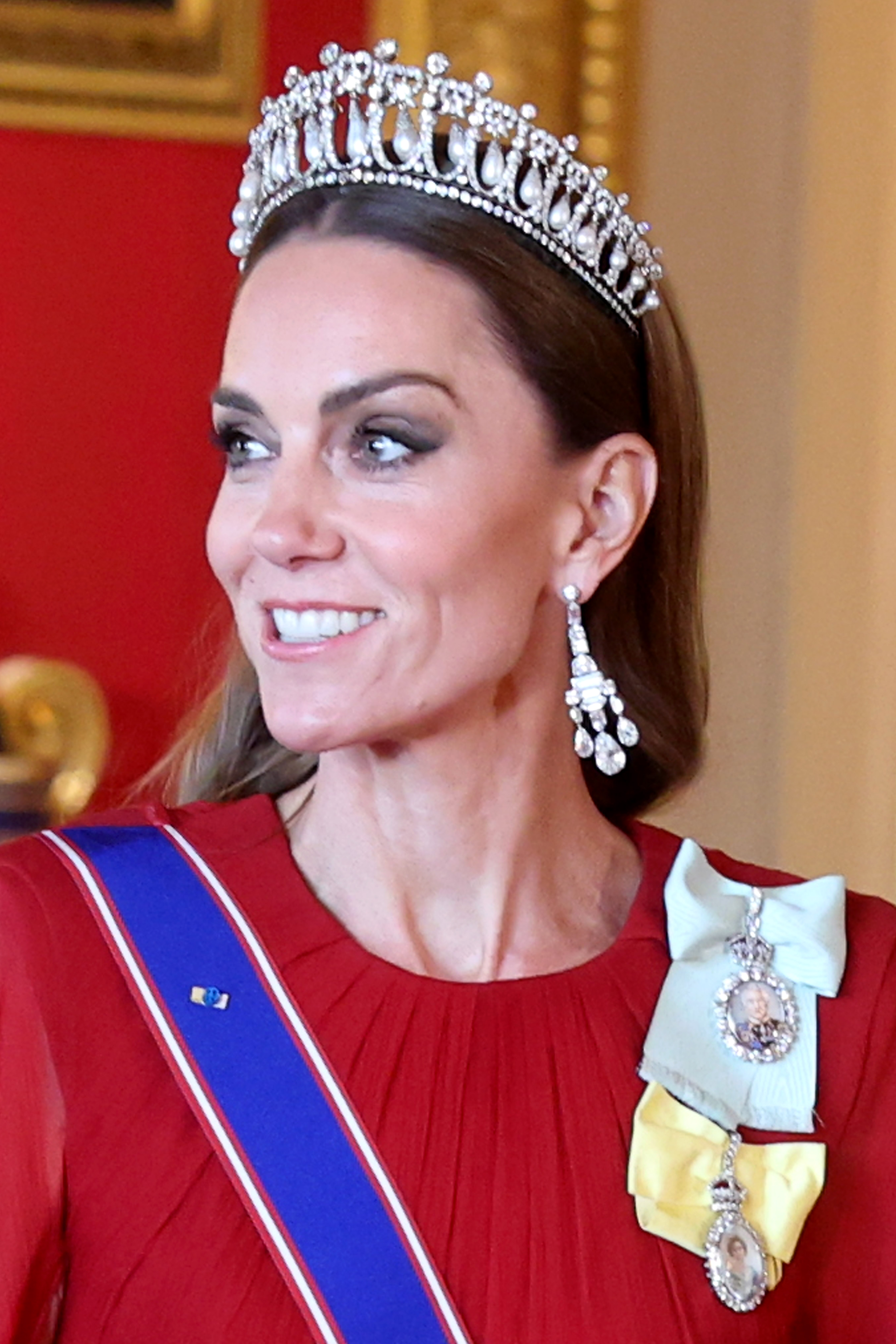 Kate Middleton wearing a red dress and tiara with royal orders