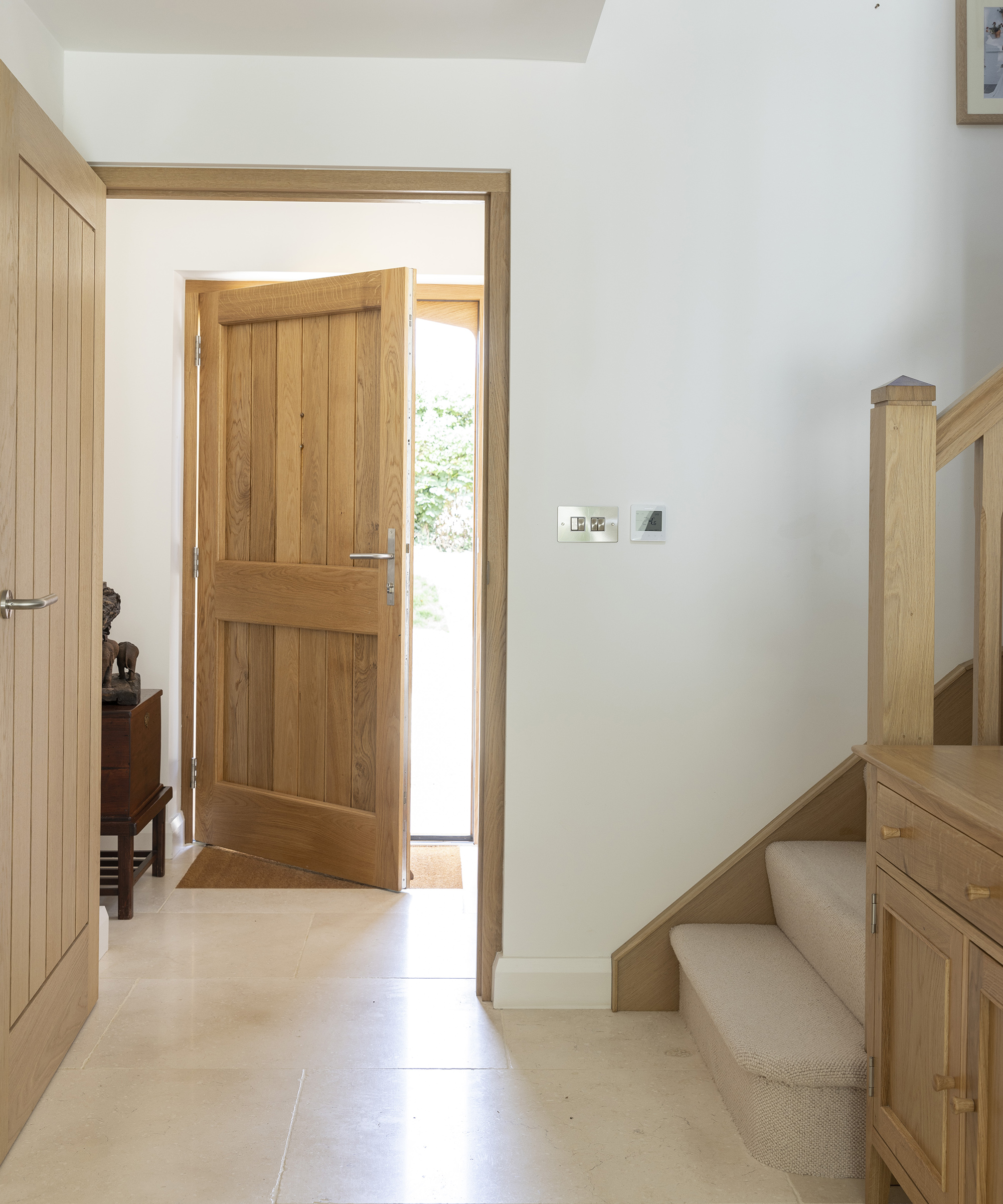 A hallway in a farmhouse style new build with staircase and doorway leading to outside