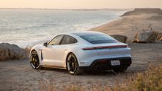 The Porsche Taycan Turbo, pictured by the beach at sunset
