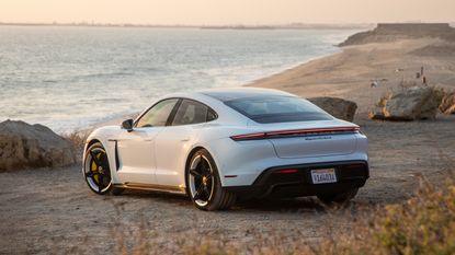 The Porsche Taycan Turbo, pictured by the beach at sunset