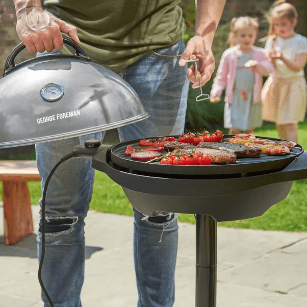 Someone using a George Foreman electric BBQ with kids in the background