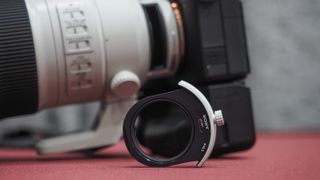 Sony FE 300mm f/2.8 GM OSS lens on a red table with grey curtains