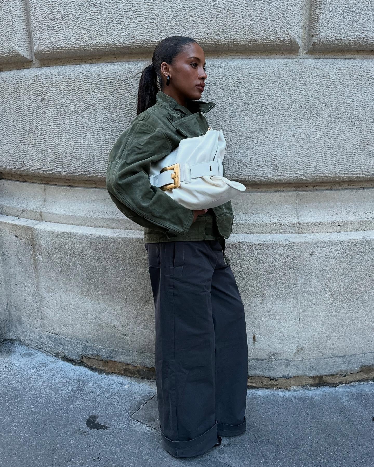 A woman wearing a green jacket with a slicked-back ponytail hairstyle