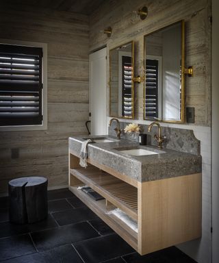 A bathroom with rustic wood panelled walls and a marble counter top double vanity