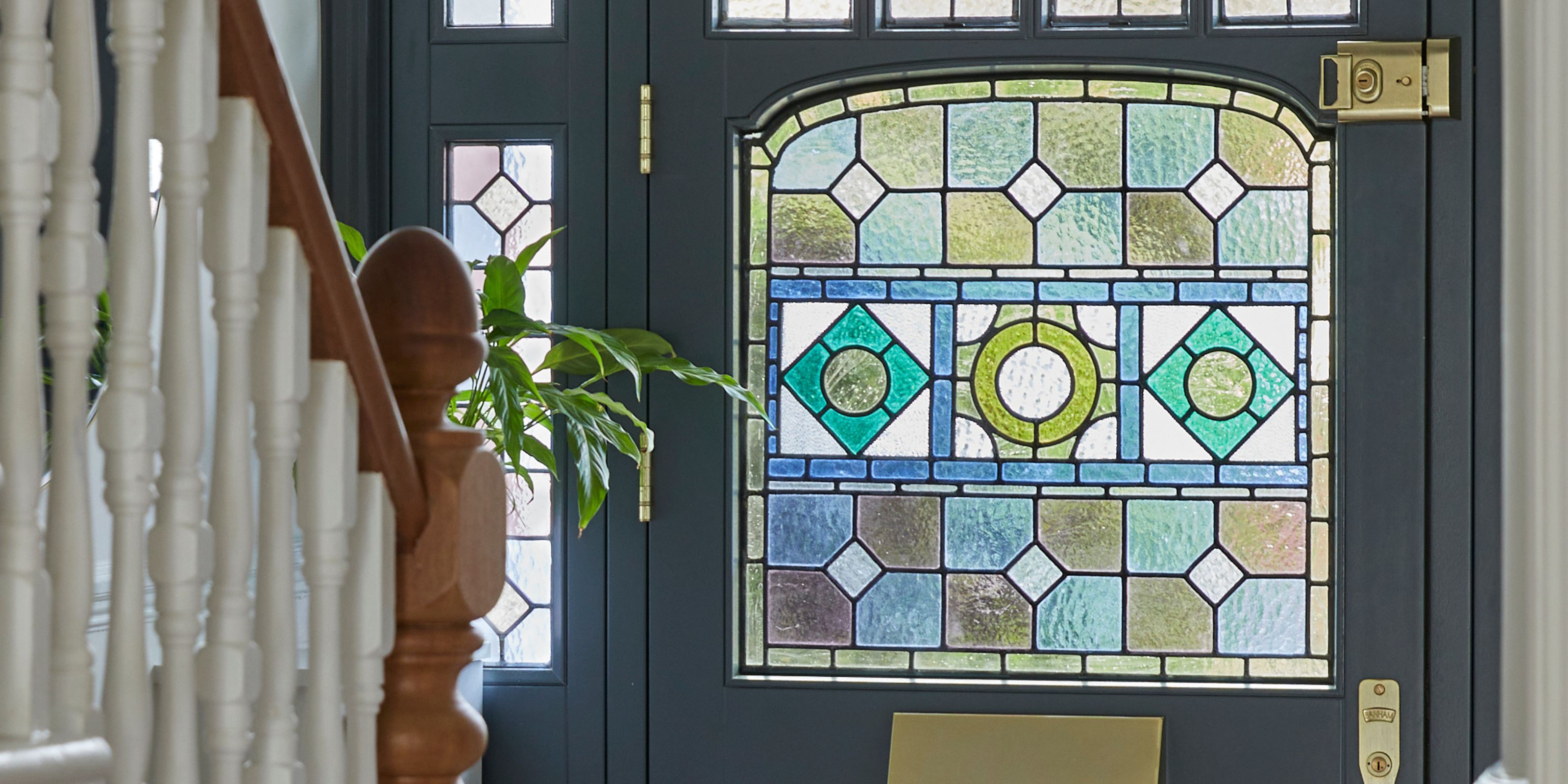 A navy front door with stained glass in blue and green