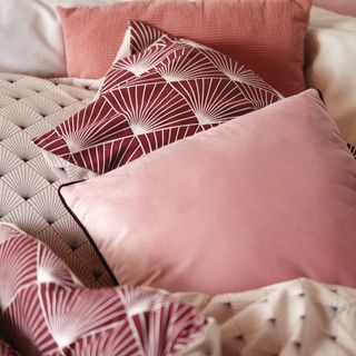bed with red and pink designed cushions