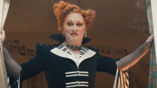 Jinkx Monsoon as Maestro in Doctor Who opening curtains and smirking.