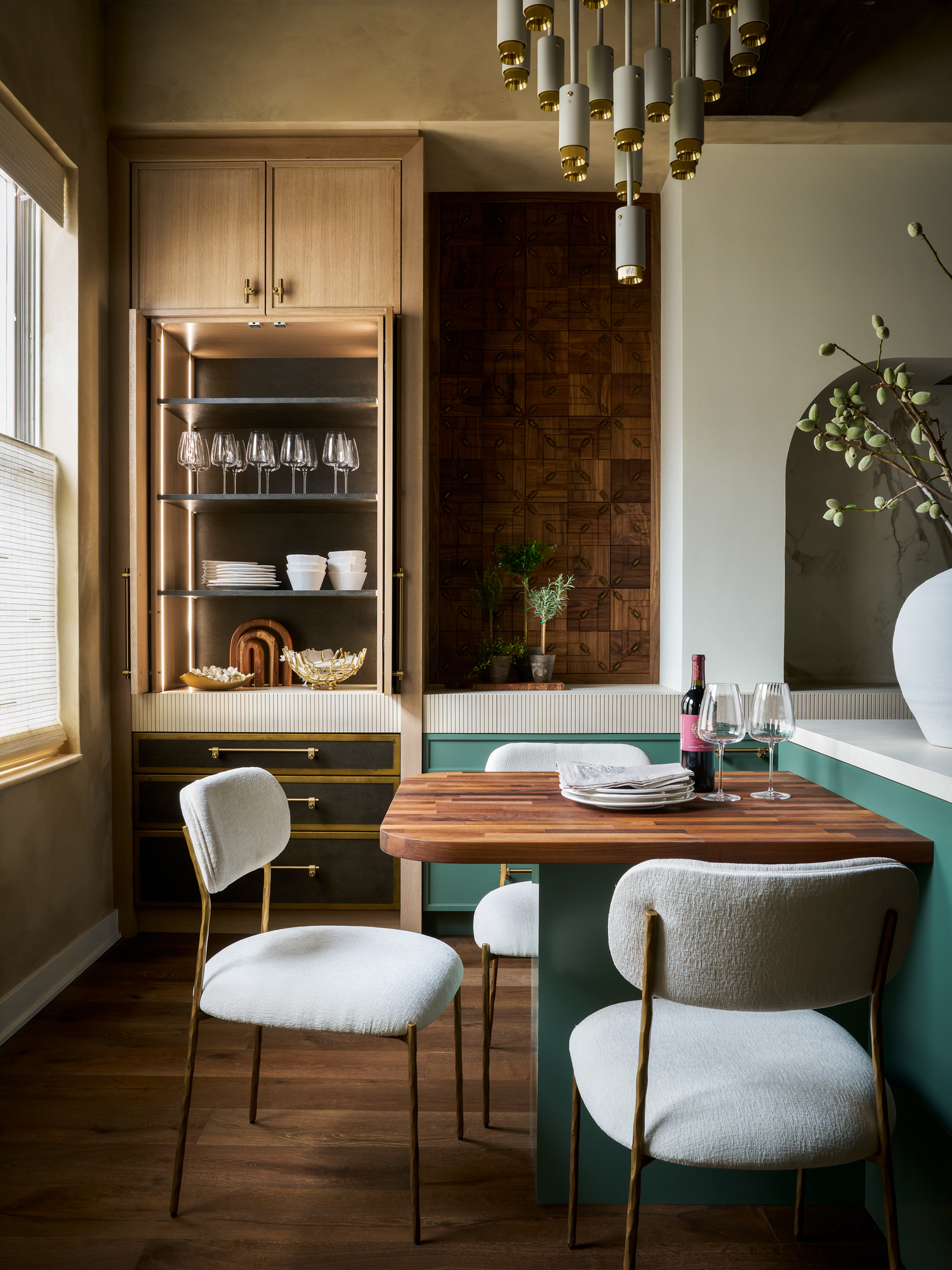 A teal and wood kitchen with and island that eases into a dining area for three