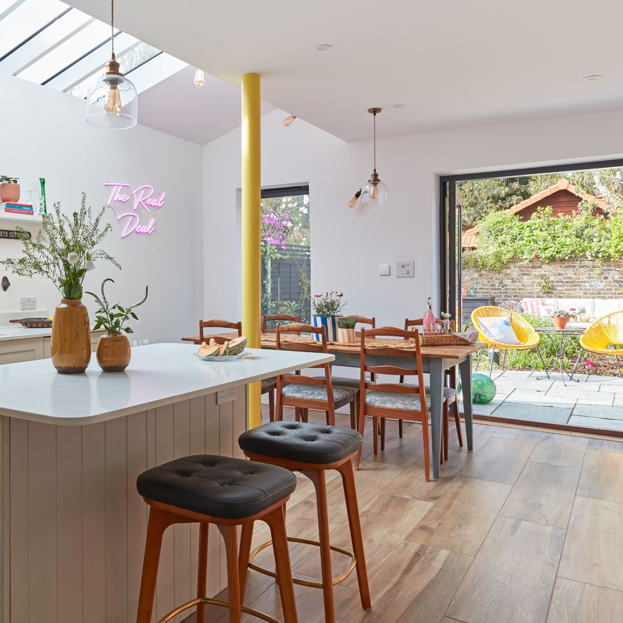 Kitchen diner area with doors leading to a patio garden, wooden dining table and chairs and a breakfast bar with stools around it