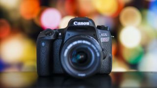 Et Canon EOS 77D kamera i fokus foran en farverig bokeh-baggrund