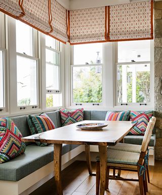 banquette seat with colorful cushions and blinds with red pattern